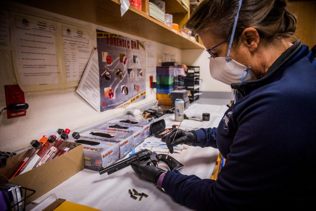 Tech dusting a handgun for prints