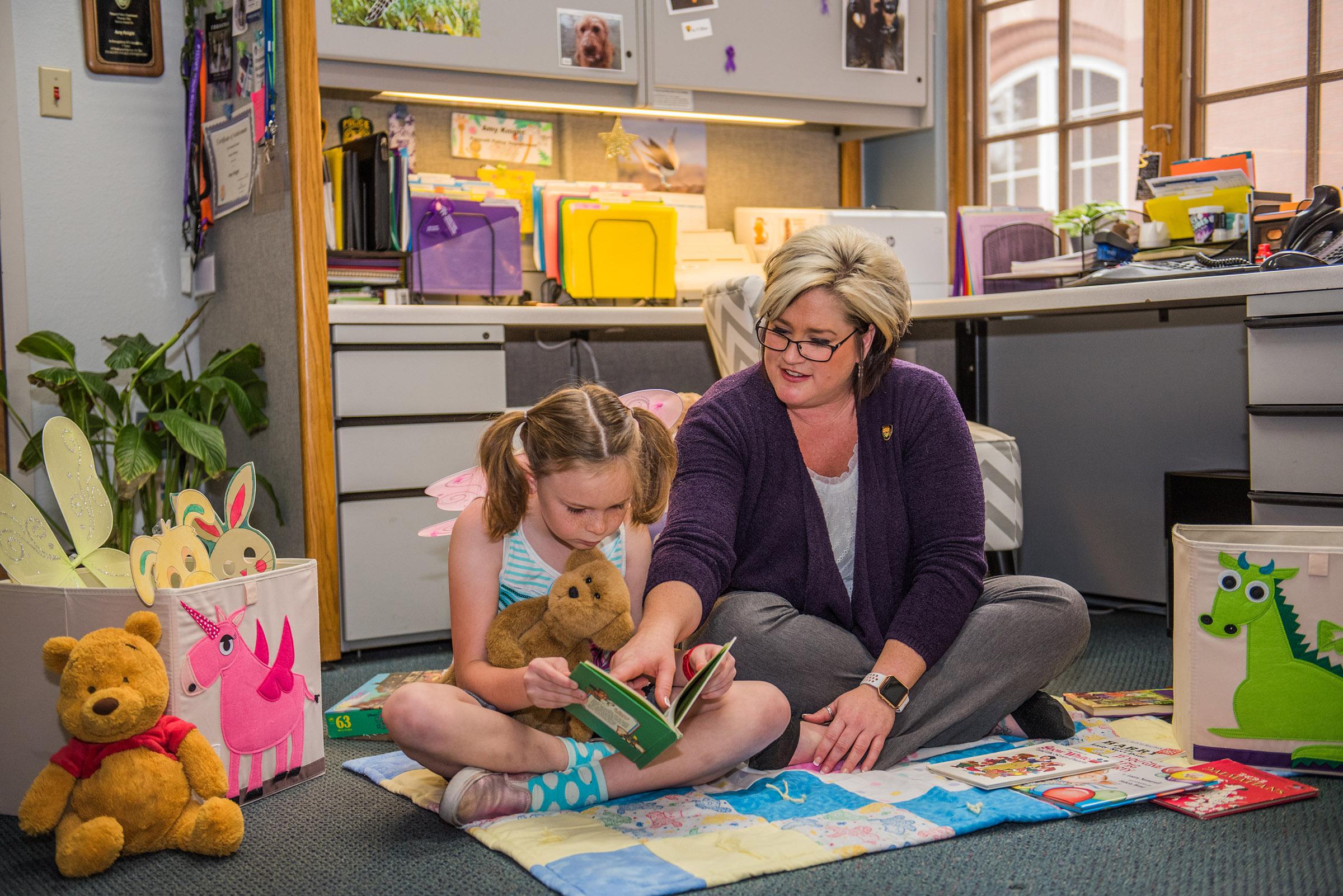 Social worker with little girl reading a book